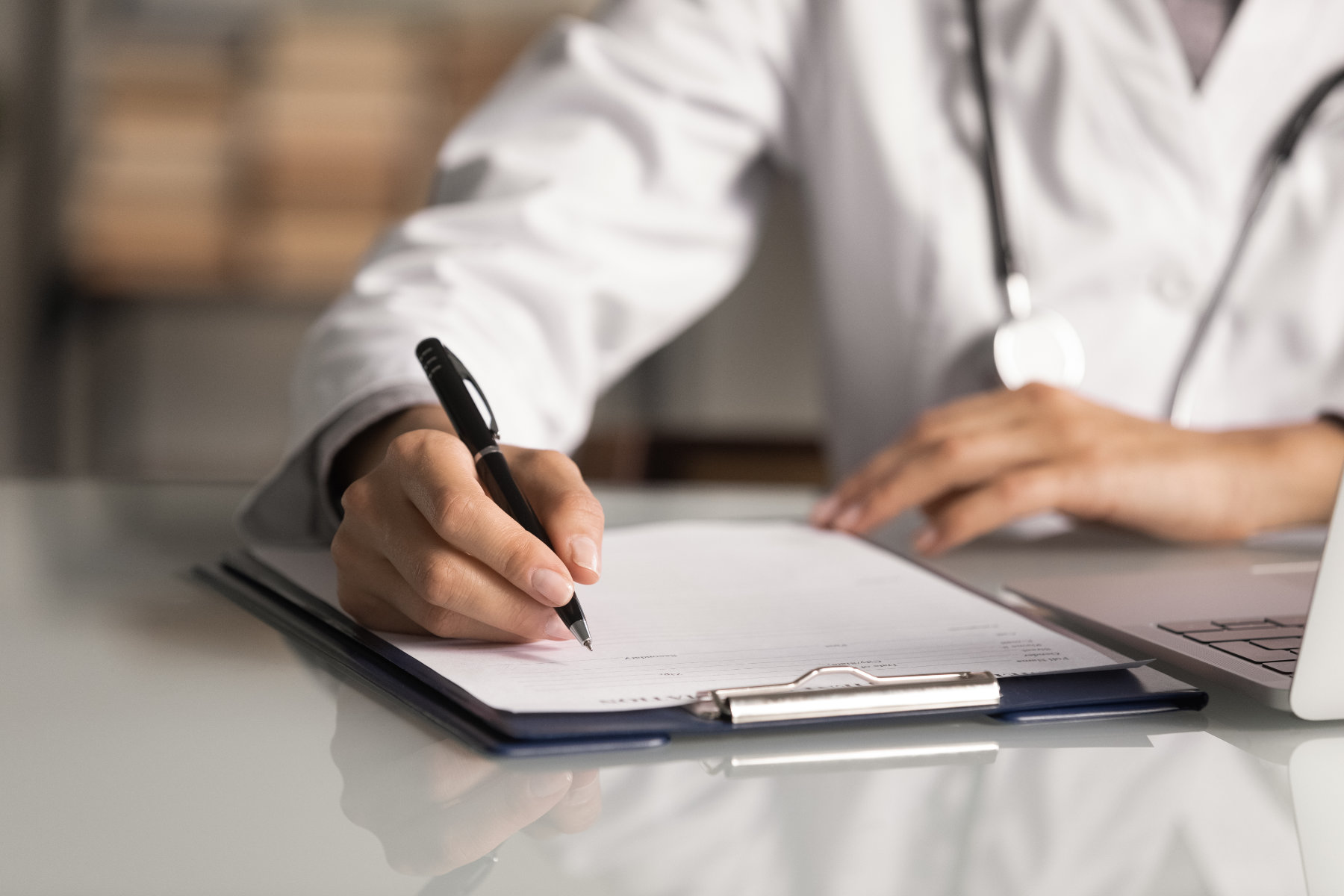 Doctor writing on medical form with clipboard, symbolising medical documentation.