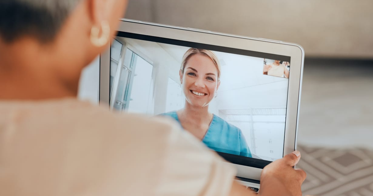 Patient attending virtual healthcare consultation with smiling medical professional.