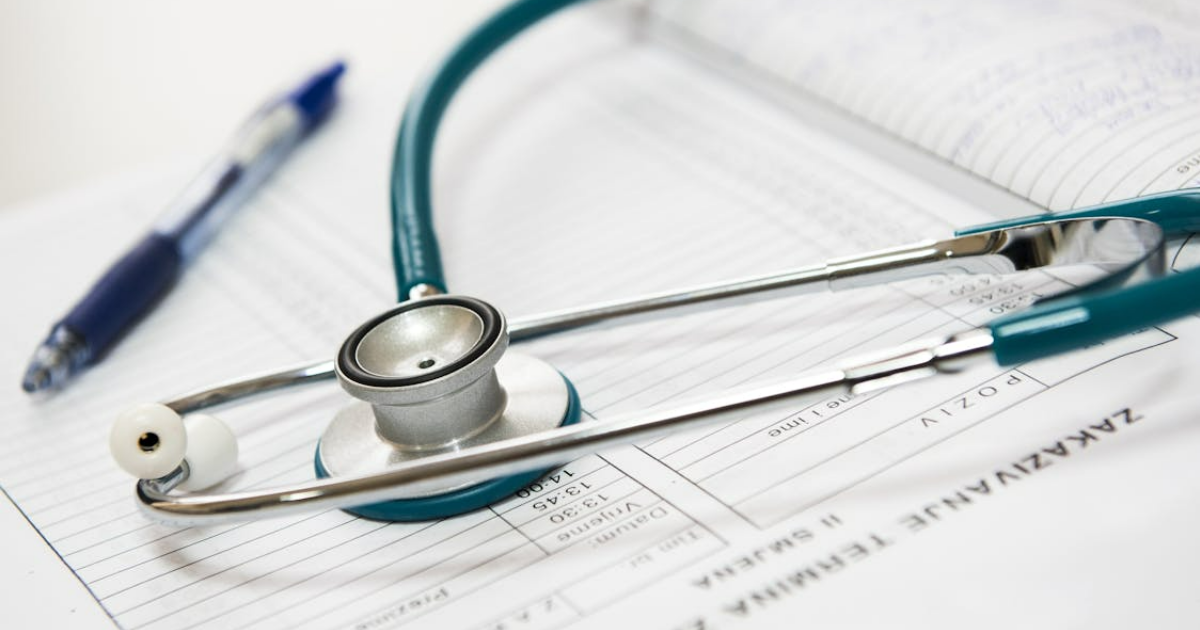 Stethoscope resting on medical consultation form with pen, representing patient assessment.