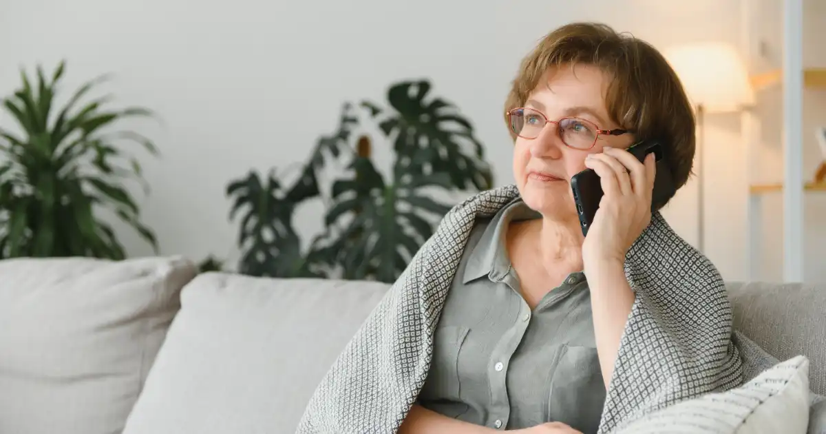 Woman using phone for a telehealth appointment in a comfortable home setting.
